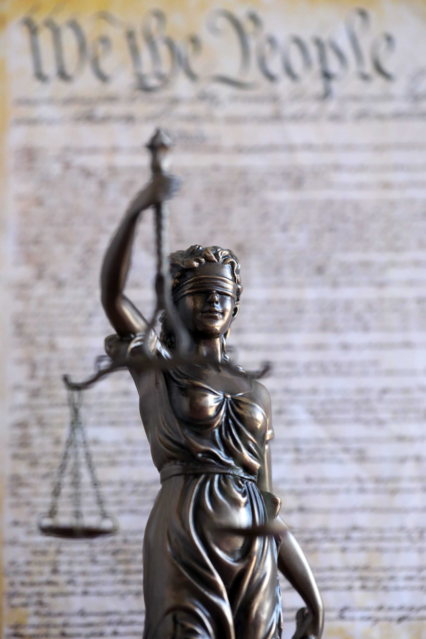 The statue of justice Themis, the blindfolded goddess of justice against US Constitution page